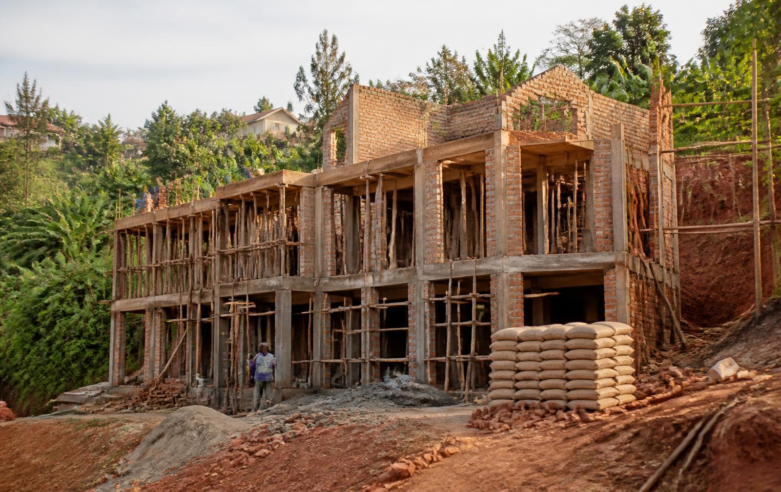 Construction site in Uganda with stacked cement bags and timber scaffolding
