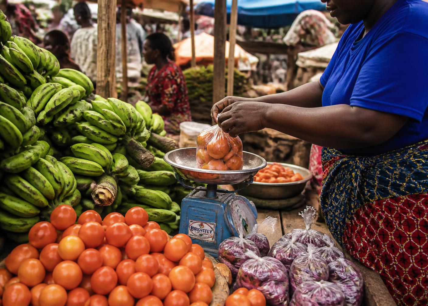 Vendor weighing tomatoes at a Kampala market stall